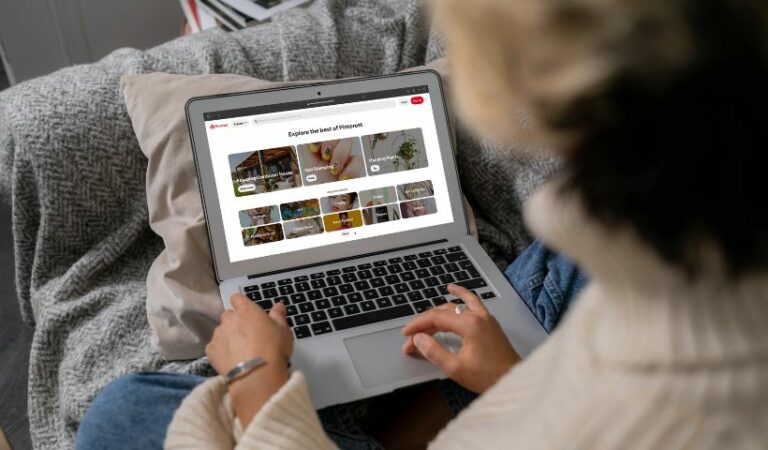 A woman using Pinterest on a MacBook, searching for popular Pinterest categories.