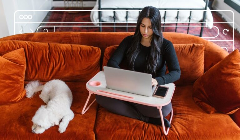 Woman working on laptop at home on orange couch with white dog beside her