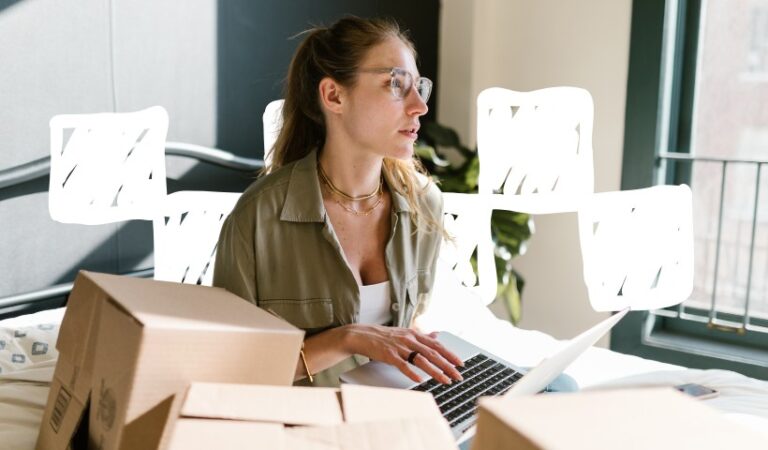 Woman working on laptop with shipping boxes, researching trending products to sell online.
